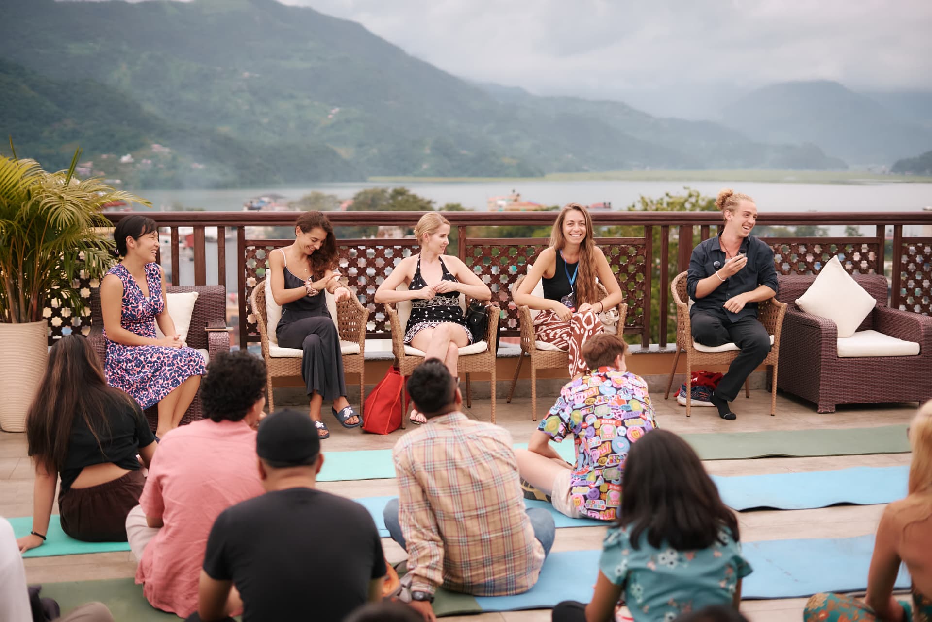 A panel discussion on a rooftop terrace overlooking Phewa Lake and the Annapurna range